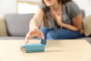 woman reaching for asthma inhaler